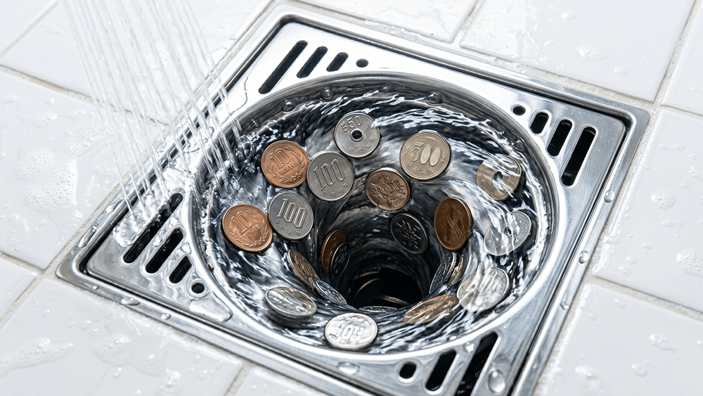排水溝に流れていく硬貨のイメージ
